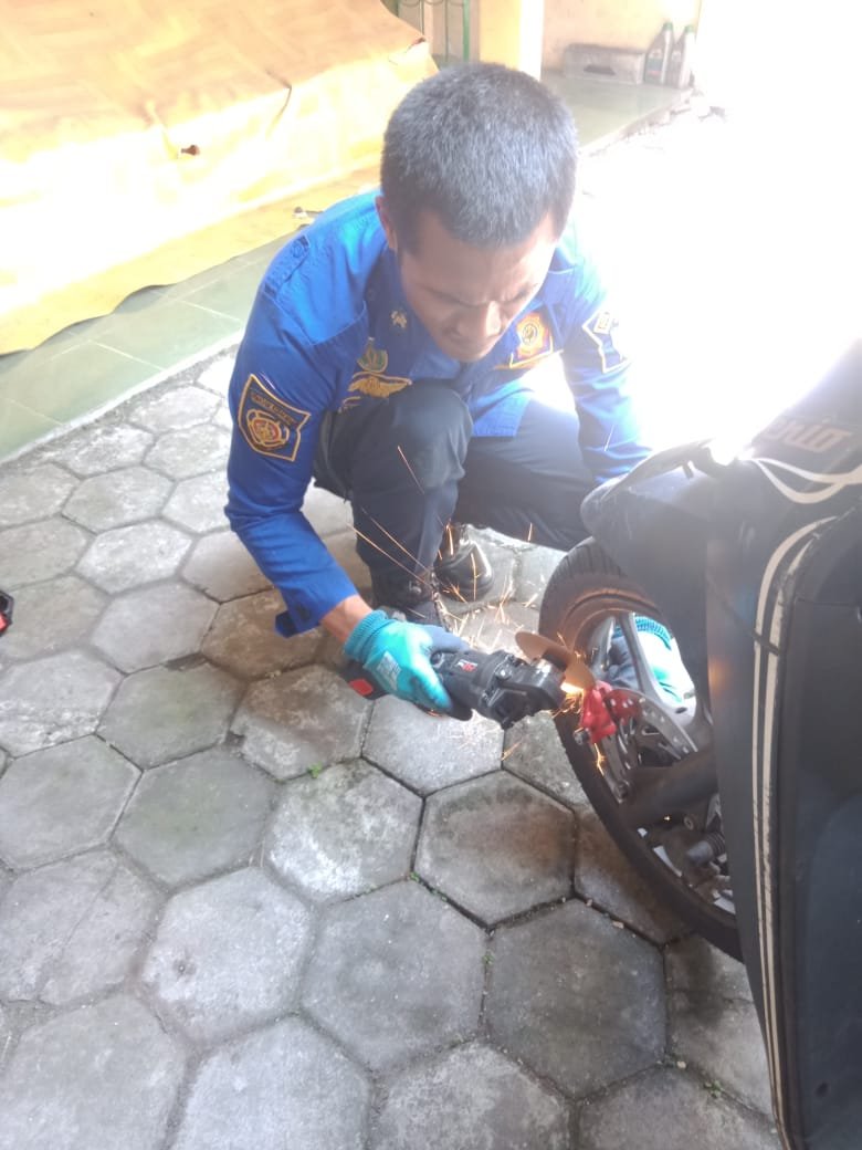 Petugas Damkar Jogja melepas kunci cakram motor yang macet dengan gerinda. (Joke)