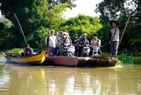 warga bersama sepeda motor mereka menaiki perahu penyeberangan tradisional saat melintasi aliran Way Bungur di Kecamatan Way Bungur, Kabupaten Lampung Timur