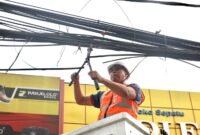 Tri Adhianto memotong jaringan kabel udara fiber optik yang semrawut di salah satu ruas jalan utama Kota Bekasi