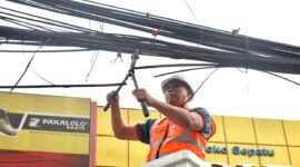 Tri Adhianto memotong jaringan kabel udara fiber optik yang semrawut di salah satu ruas jalan utama Kota Bekasi