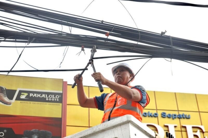 Tri Adhianto memotong jaringan kabel udara fiber optik yang semrawut di salah satu ruas jalan utama Kota Bekasi